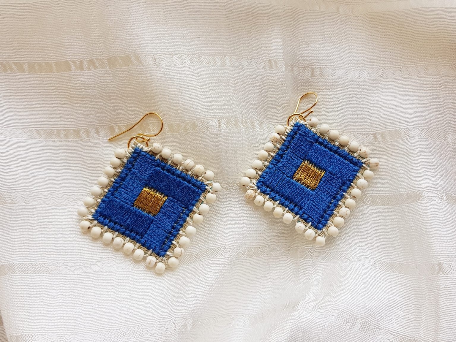 Blue hand-stitched earrings with white howlites
