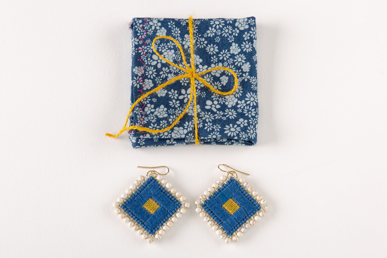 Blue hand-stitched earrings with white howlites